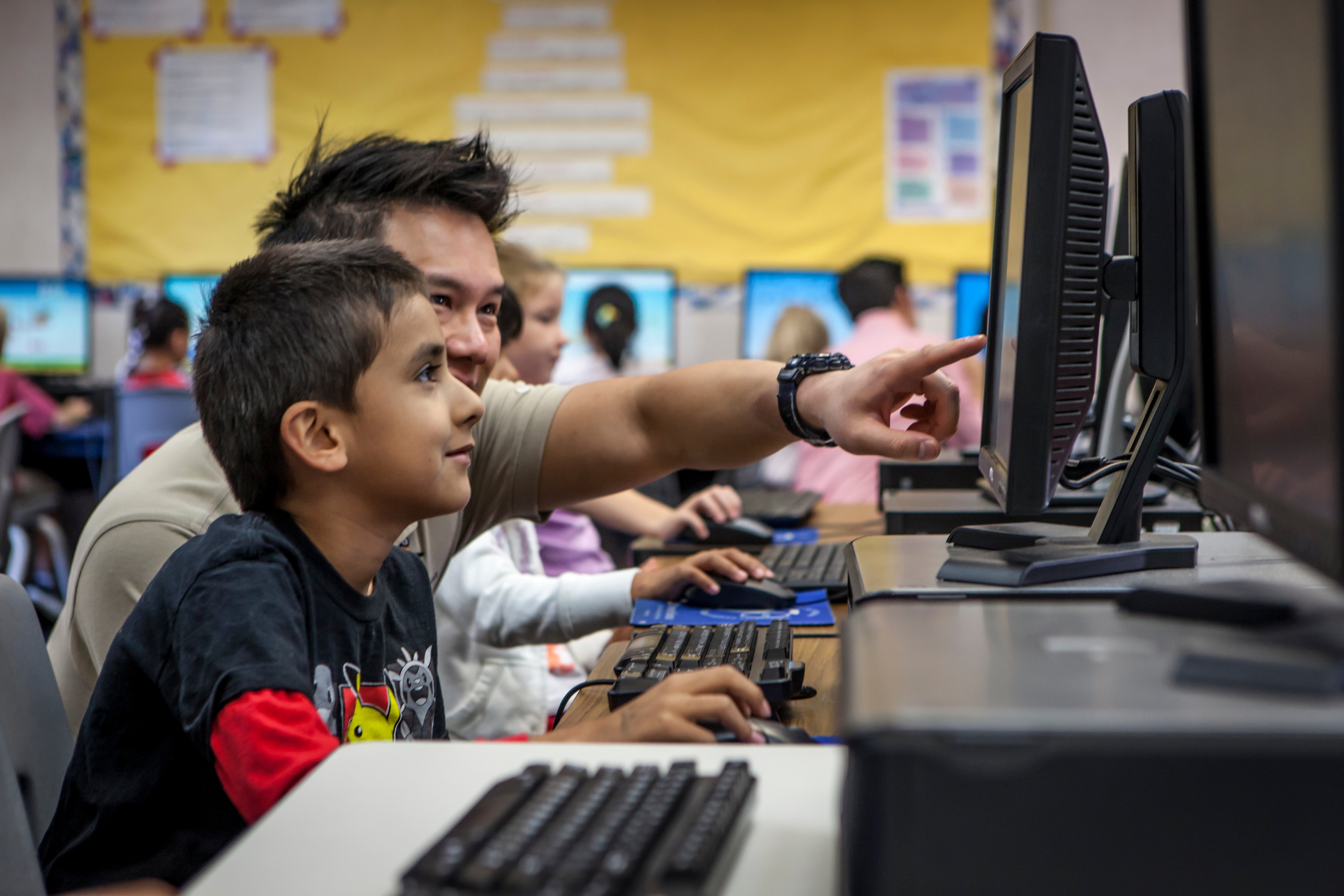 boy-teacher-pointing-computer-lab.jpg