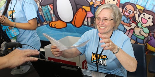 Photo of volunteer smiling, handing out materials.
